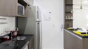 A modern kitchen with stainless steel appliances, wooden cabinets, and a black countertop. - Bright Studio - GRU (Guarulhos)