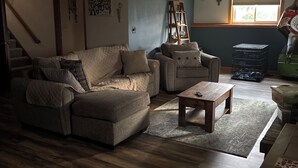 A living room with a sofa, coffee table, and a ladder against a wall. - Spacious Home that is close to EAA and Shopping. (Oshkosh)