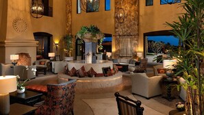 Eine großzügige Lobby mit einer zentralen Sitzgelegenheit, mehreren Sofas und einem großen Zierpflanzentopf.