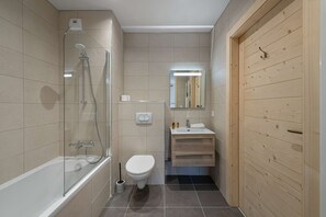 A modern bathroom with a glass-enclosed shower, a toilet, and a sink with a wooden vanity.
