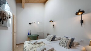 A bedroom with a bed, two wall-mounted lights, a desk, and a chair. - PERLE DE SAVOIE A402 (CHATEL)