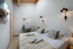 Une chambre à coucher comprenant un lit, deux lampes fixées au mur, un bureau et une chaise.