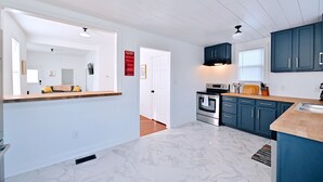 A modern kitchen with blue cabinets, a stainless steel oven, and a marble floor.
