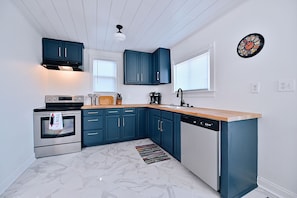 A modern kitchen with dark blue cabinets, a stainless steel oven, a dishwasher, and a wooden countertop. - Urban Comfort & Cozy 4BR Near Downtown Indianapolis (Indianapolis)