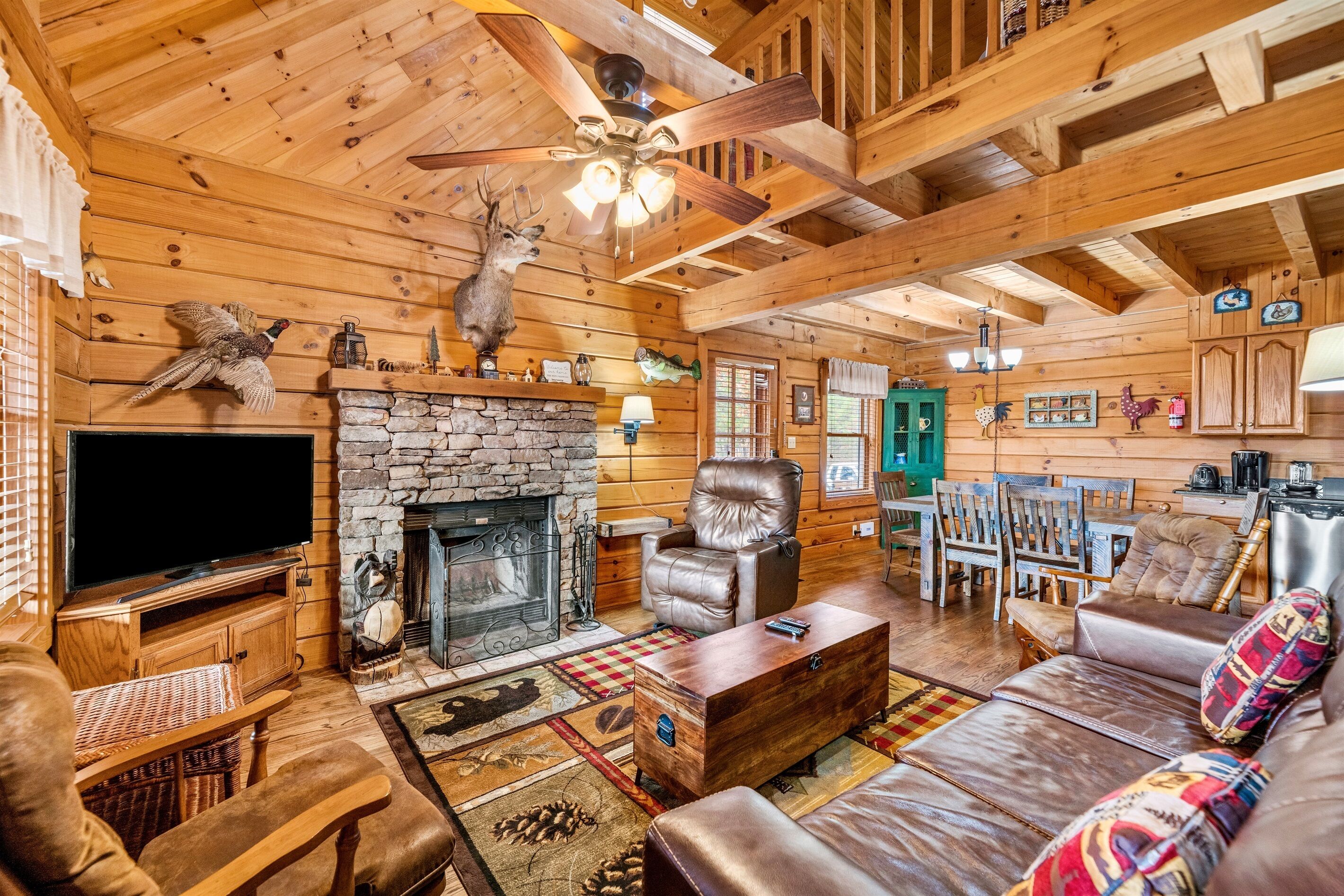 A cozy log cabin interior with a stone fireplace, leather furniture, and rustic decor.