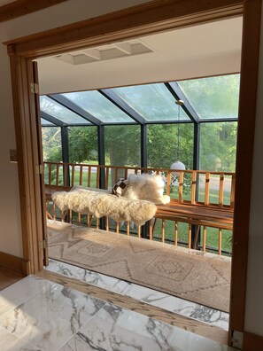 A room with a large glass window and a view of greenery outside.