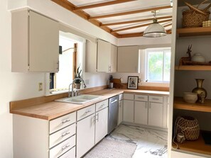 A kitchen with white cabinets, a wooden countertop, a sink, and a window.