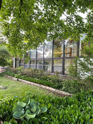 Een modern gebouw met grote ramen, omringd door weelderige begroeiing en een verzorgde tuin.