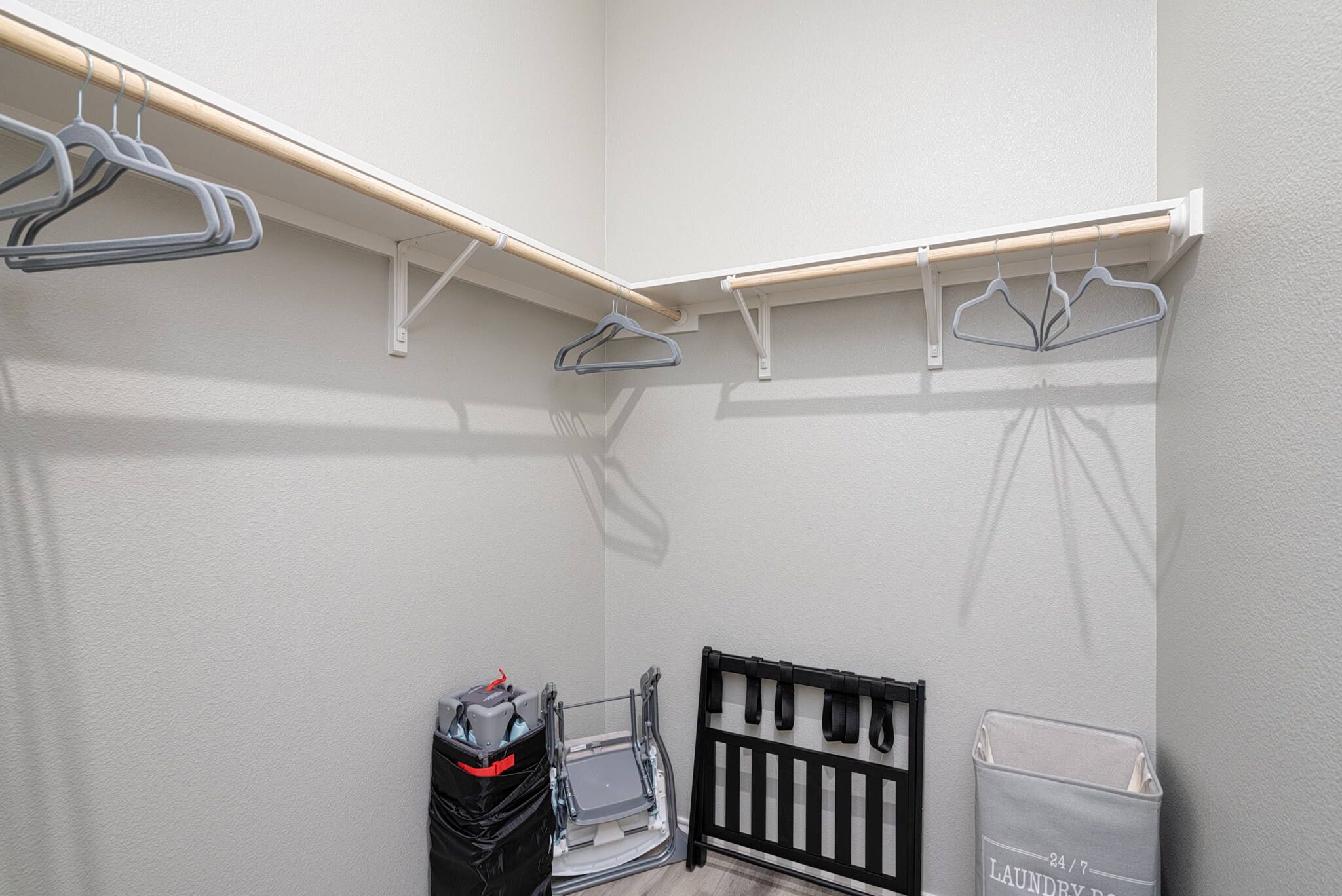 A storage closet with shelves, a black baby crib, and a laundry basket.