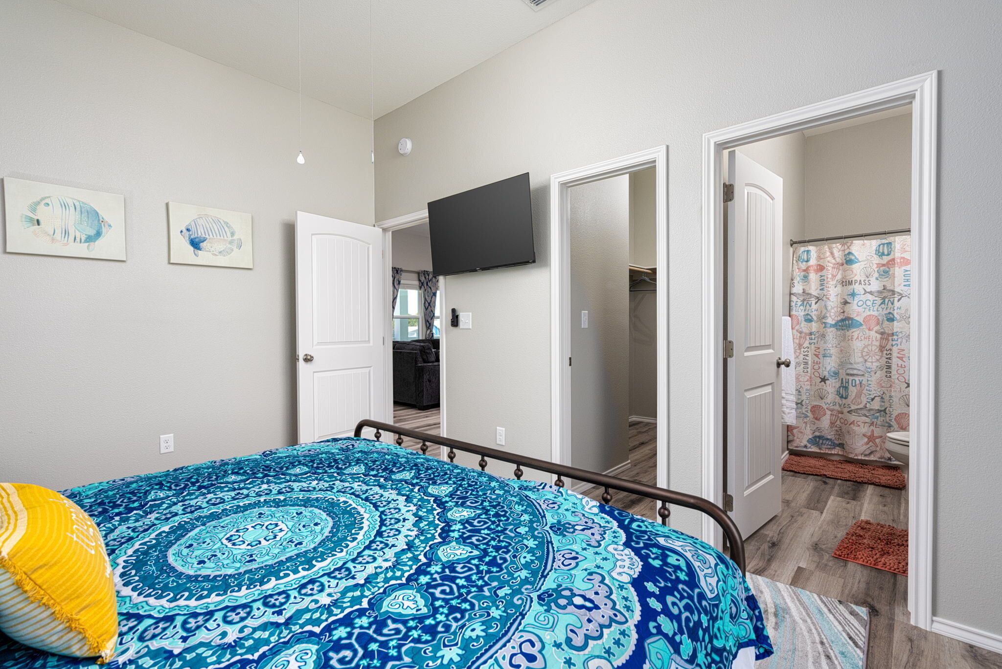 A bedroom with a bed, a television, and a bathroom visible through an open door.