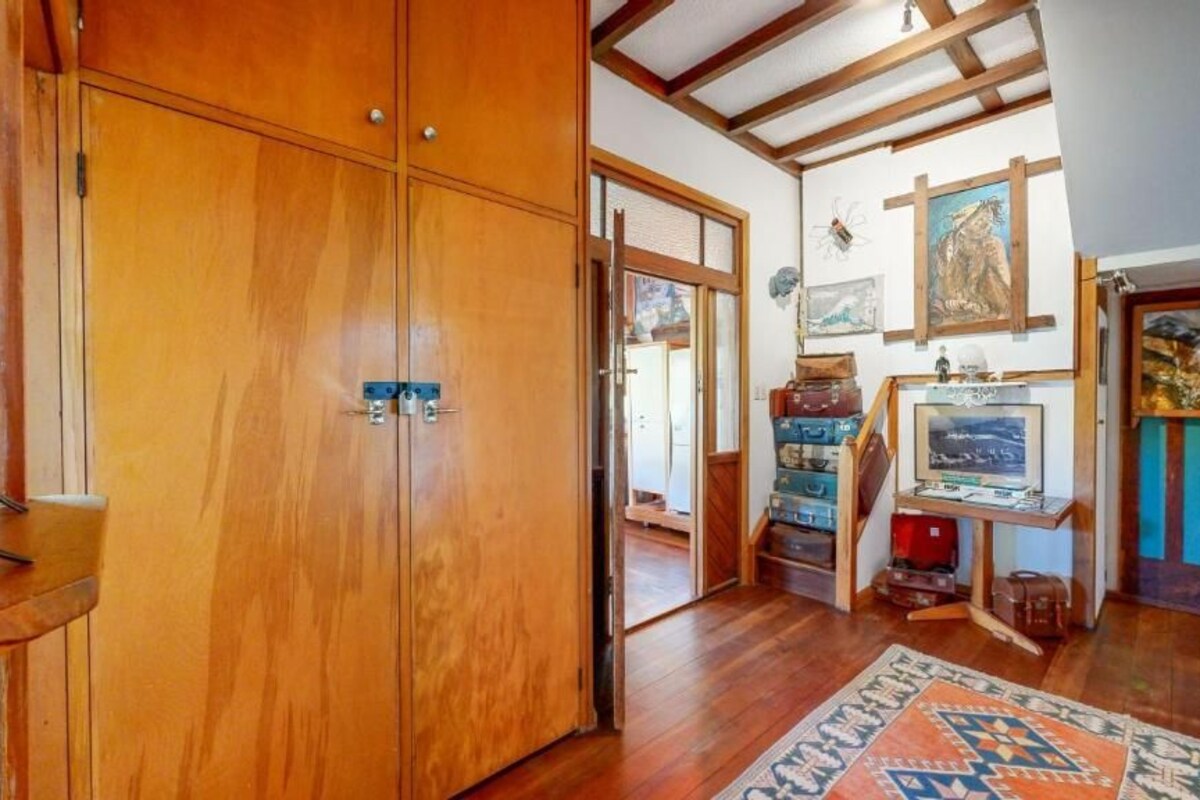 A wooden wardrobe, a rug, and artwork on the wall.