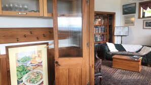 Un salón acogedor con puerta de madera, una estantería, un sofá de cuero y un comedor con un cuadro enmarcado.