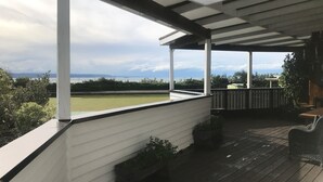 Una terraza techada al aire libre con vistas a un campo verde y una masa de agua.