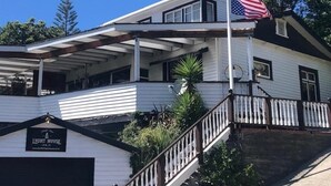 Un edificio de dos pisos con un porche cubierto, un asta con la bandera estadounidense y un cartel que dice 'Light House'.