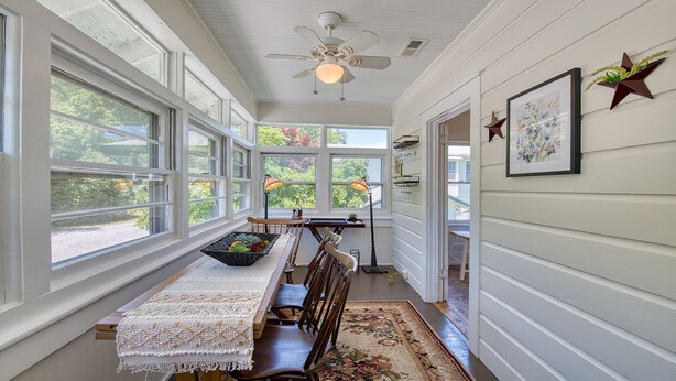 A sunlit dining area with a long table, chairs, and a ceiling fan. - Historic Carriage House - Downtown Waynesville, Walk to Main Street! Fast Wifi! (Waynesville)
