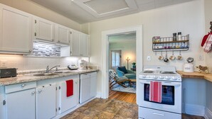 A kitchen with white cabinets, a stove, and a coffee maker. - Historic Carriage House - Downtown Waynesville, Walk to Main Street! Fast Wifi! (Waynesville)