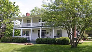 A two-story house with a front porch, a chimney, and a well-maintained lawn. - Historic Carriage House - Downtown Waynesville, Walk to Main Street! Fast Wifi! (Waynesville)