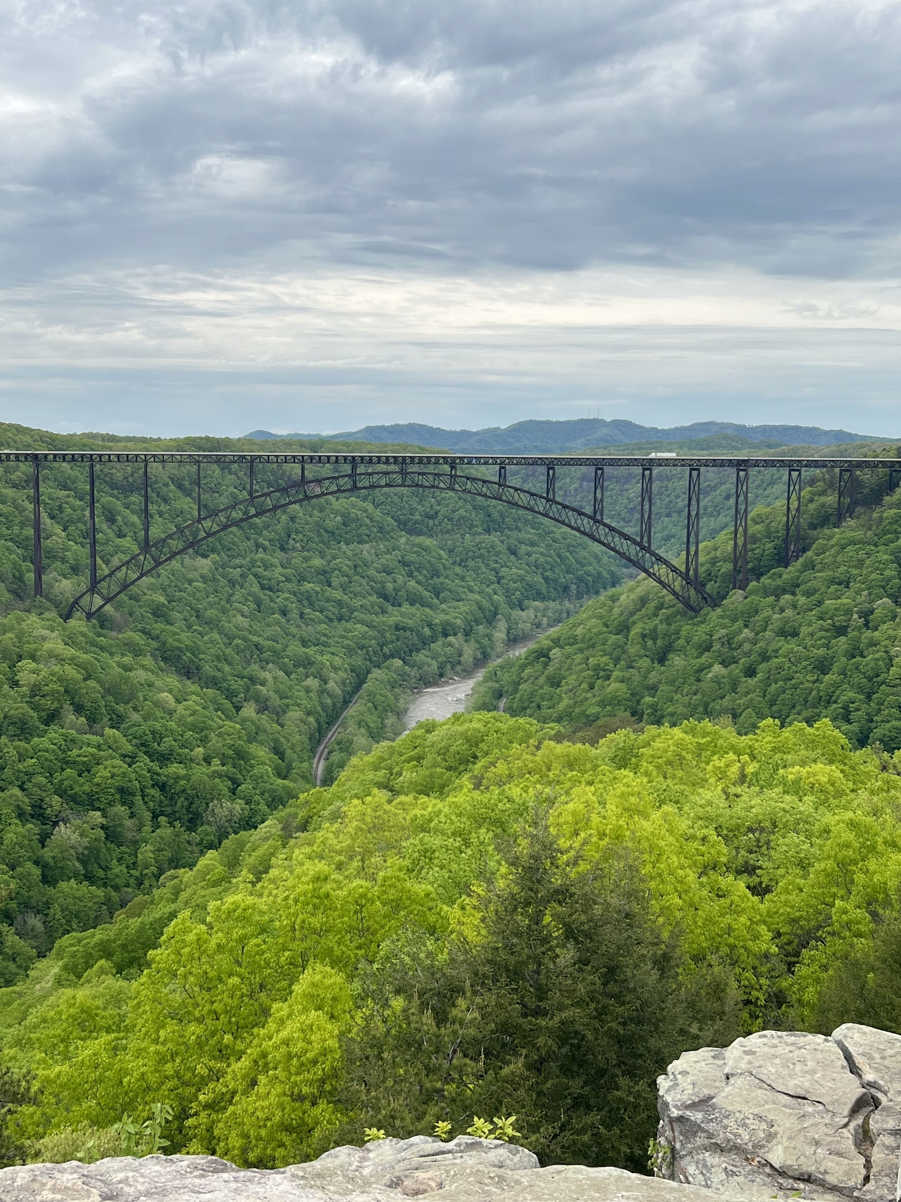 Un pont d’acier enjambant une rivière dans une vallée boisée.