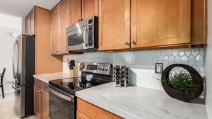 A modern kitchen with wooden cabinets, stainless steel appliances, a marble countertop, and a built-in wine rack. - Fall Special! Private Pool/Spa! (Chandler)