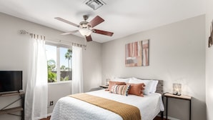 A bedroom with a bed, a ceiling fan, a TV, a bedside table, and a window with curtains. - Fall Special! Private Pool/Spa! (Chandler)