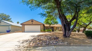 A single-story house with a garage, a stone patio, and a large tree in front. - Fall Special! Private Pool/Spa! (Chandler)