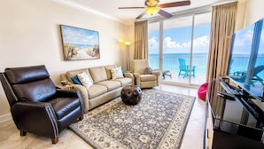 A living room with a sofa, armchair, ottoman, and a piano. - Avalon 1707 King/Queen- Direct Gulf View - Wifi (Gulf Shores)