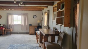 Une pièce chaleureuse avec un plafond en bois, un canapé, une table à manger et une fenêtre avec des rideaux.
