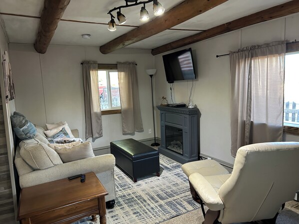 A living room with a sofa, armchair, ottoman, and a fireplace.