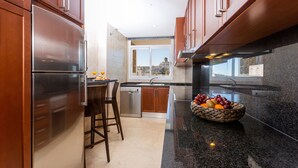 Una cocina moderna con armarios de madera, un refrigerador de acero inoxidable, un lavavajillas y una encimera de granito.