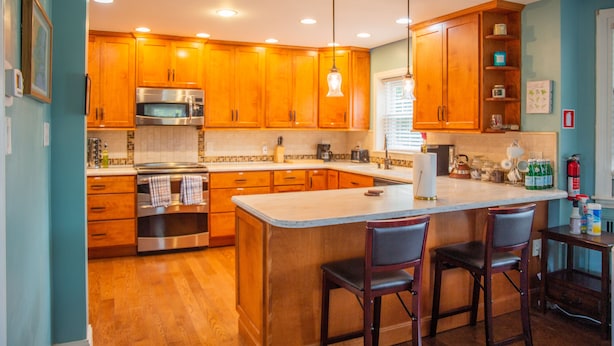 Una cocina con armarios de madera, electrodomésticos de acero inoxidable y una isla central con taburetes de bar.