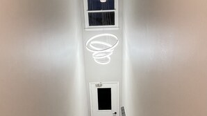 Un couloir étroit avec un escalier recouvert de moquette menant à une porte.