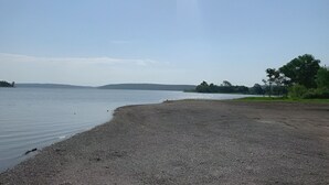 Una playa pedregosa con agua tranquila y colinas a lo lejos.