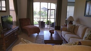 A living room with a sofa, armchair, coffee table, and a television. - Welcome to your South West Florida Paradise! (Estero)