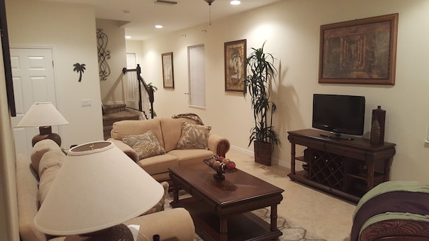 A living room with a sofa, coffee table, TV, and decorative items. - Welcome to your South West Florida Paradise! (Estero)