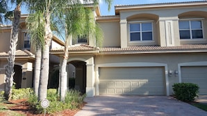 A two-story house with a garage, a covered patio, and a well-maintained garden with palm trees. - Welcome to your South West Florida Paradise! (Estero)