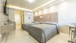 Habitación de hotel con dos camas, baño, escritorio y televisor.