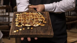 Una persona sosteniendo una tabla de madera con un postre.