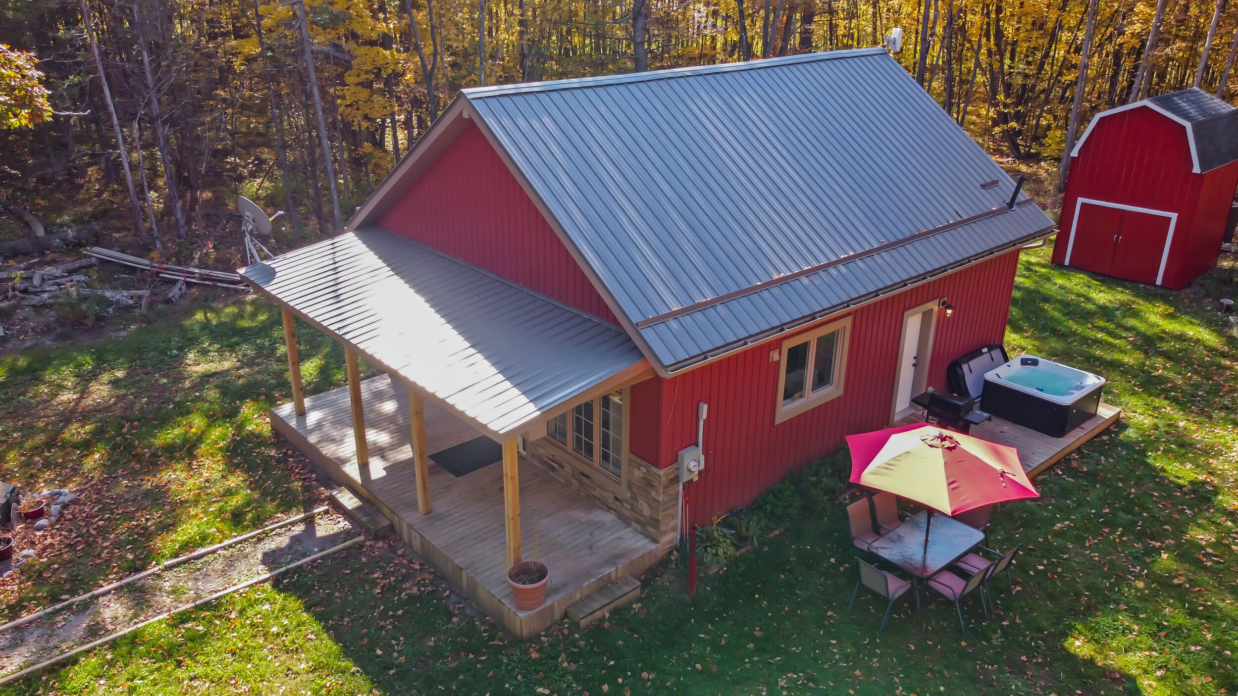 A red cabin with a porch and a hot tub.