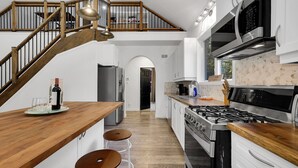 Una cocina moderna con escalera de madera, electrodomésticos de acero inoxidable y vistas al comedor.