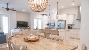 Eine moderne Küche mit weißen Schränken, einem Holzespeisetisch und einer Chandelier.