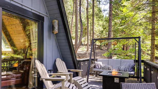 Een terras met Adirondack-stoelen, een bank en een vuurplaats.