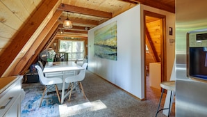 Een gezellige zolderkamer met een eettafel, stoelen en een schilderij aan de muur.