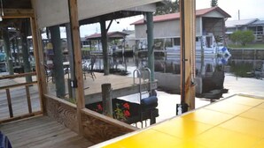 A covered outdoor area with a wooden deck, a metal railing, and a view of a dock and water. -  Canal  access to the St. Johns River. Private boat dock. Parking for  trailer (Welaka)