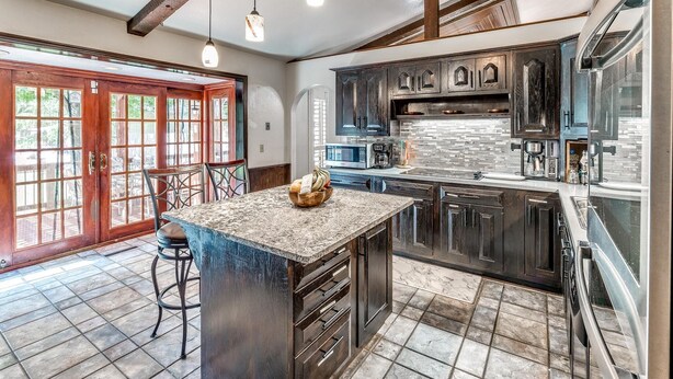 Una cocina amplia con alacenas de madera oscura, encimera de granito y una isla grande con taburetes de bar.