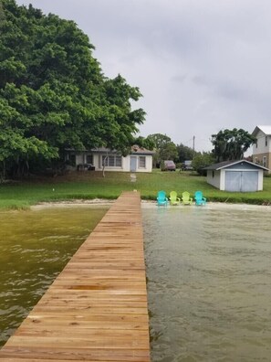 A wooden dock leading to a house with a small shed and two green chairs by the water. - Lakefront getaway with white sand, clear water, gorgeous sunsets (Lake Placid)