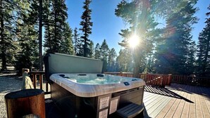 Un jacuzzi en una terraza de madera rodeada de árboles.