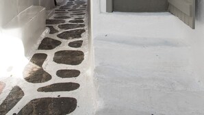 Un estrecho pasillo con suelo de baldosas de piedra, una escalera con barandilla de madera y una puerta con la leyenda "Parku".