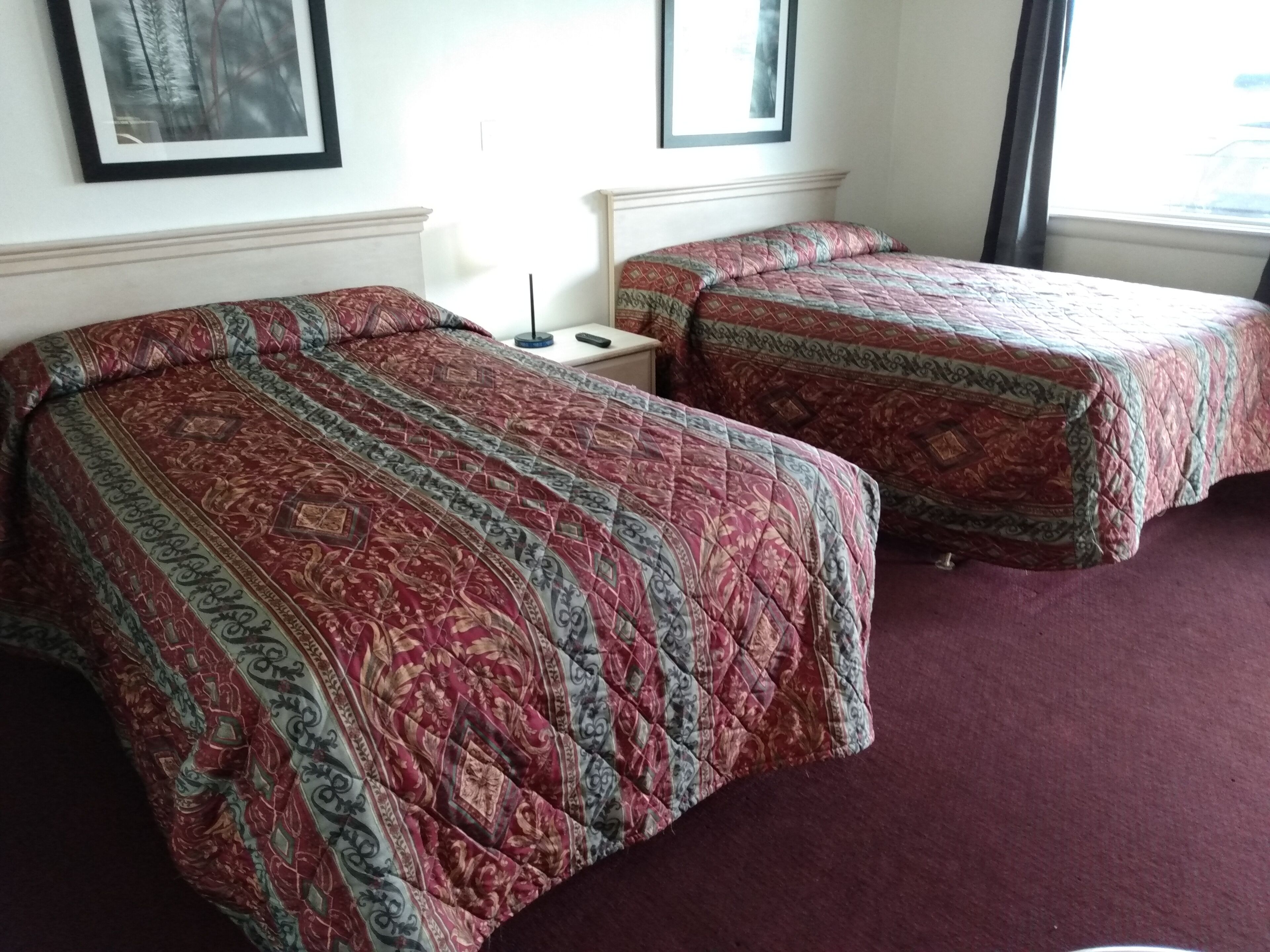 Two single beds with patterned quilts, a bedside table, and a nightstand.