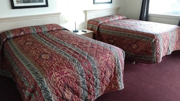 Two single beds with patterned quilts, a bedside table, and a nightstand.