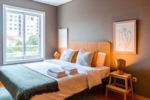 Relax in a spacious room with a large bed, framed artworks, and a window offering a view of the surrounding area.